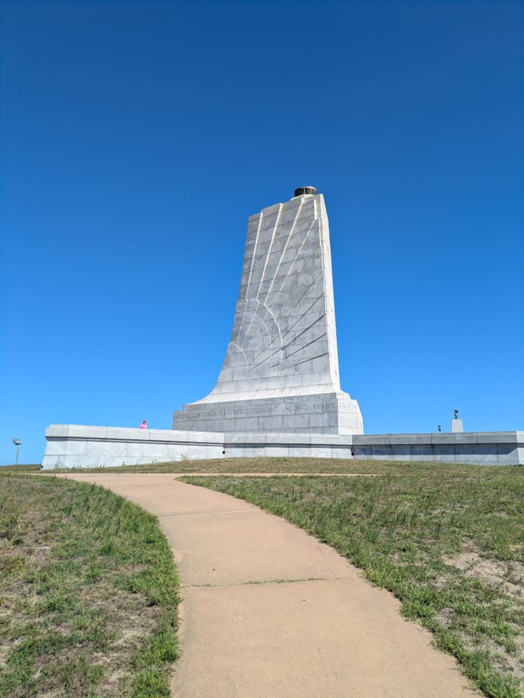 Kitty Hawk monument -- large granite, wing shaped structure with grass in foreground and blue sky. 