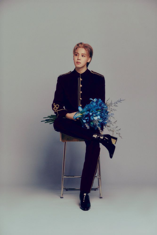 Park Jimin of BTS holding a blue flower bouquet on his lap