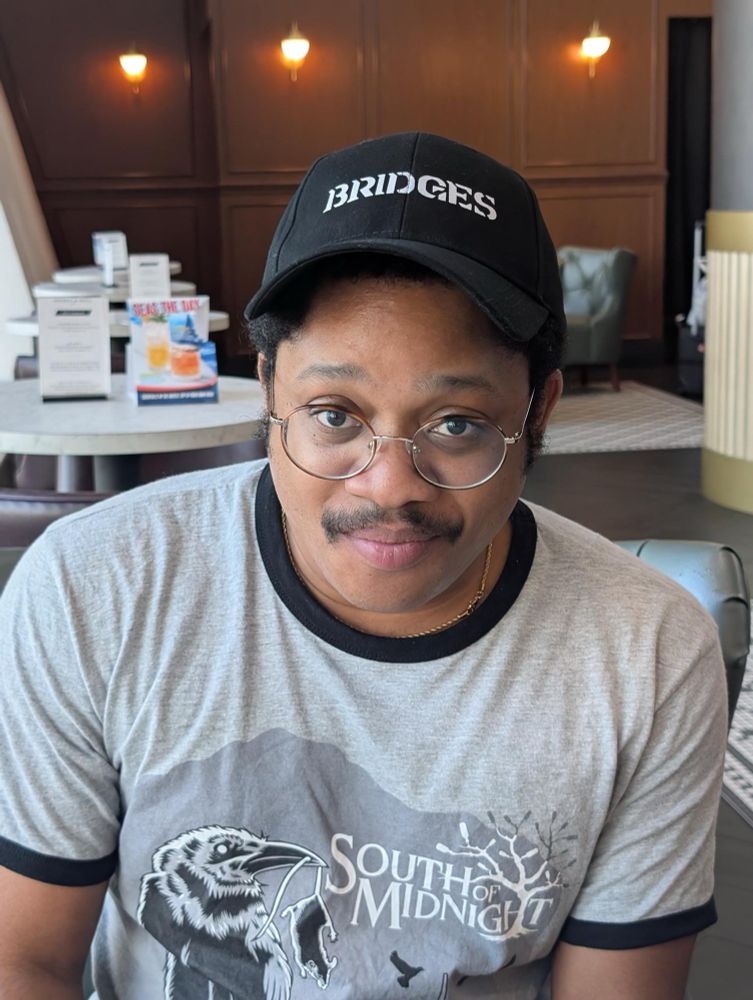 black man in south of midnight dev tee and bridges hat 