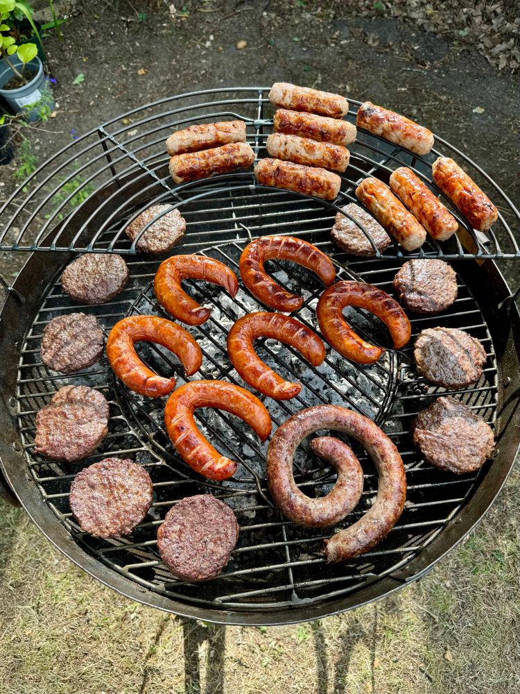 Bangers, burgers, kielbasa, and boerewors, all on a BBQ grill. 