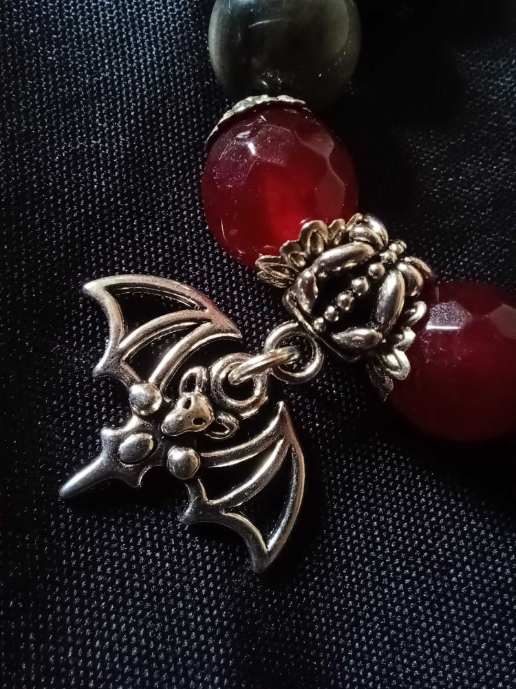 A close up picture of the silver bat charm on one of the bracelets. 