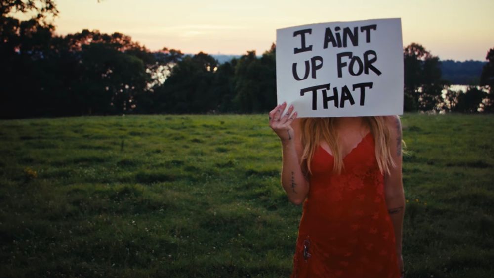 Margo Price is holding a sign that says “I Ain't Up For That.” It's a screenshot from the video for her song “Don't Wake Me Up.”