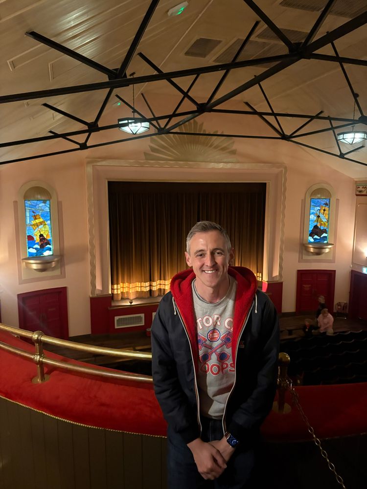 Lewis Atkinson inside cinema, overlooking screen and stained glass windows 