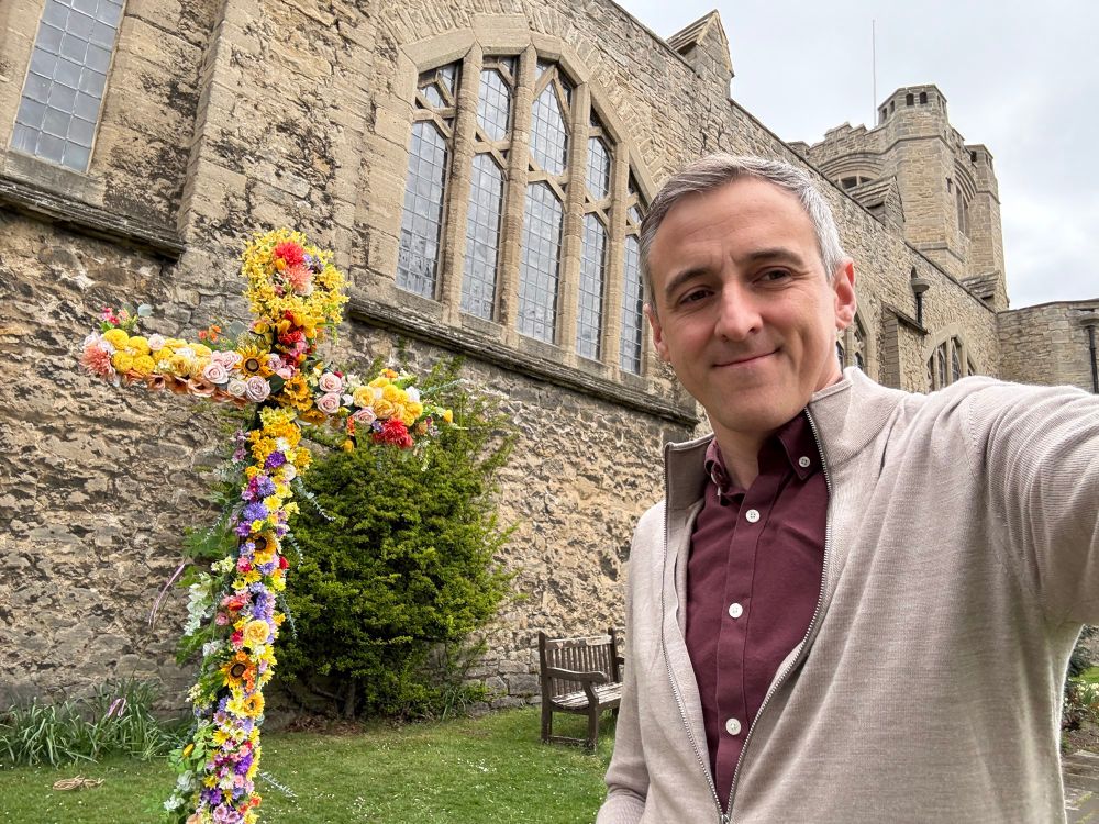 Lewis Atkinson MP next to Easter floral cross in front of church
