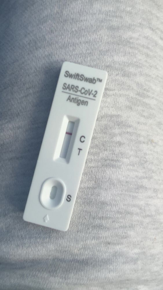 A negative covid test sitting on my gray sweatpants 