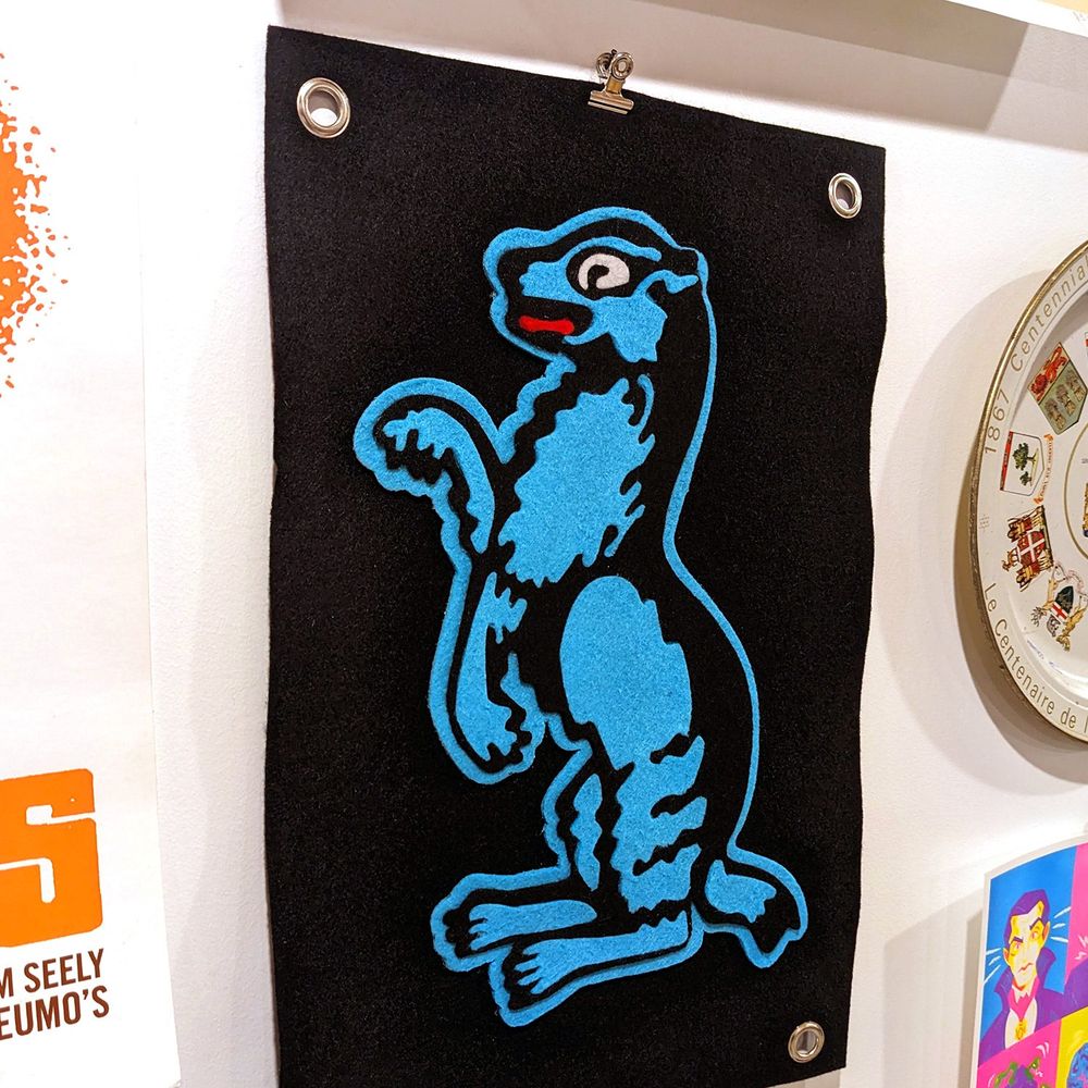 A felt flag with a blue and black badger design on it.