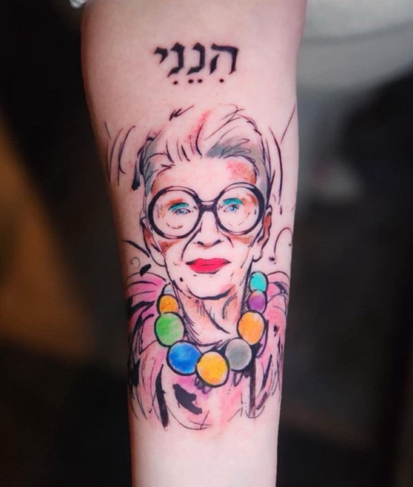 A watercolor style tattoo of style icon Iris Apfel tattooed on a forearm. 