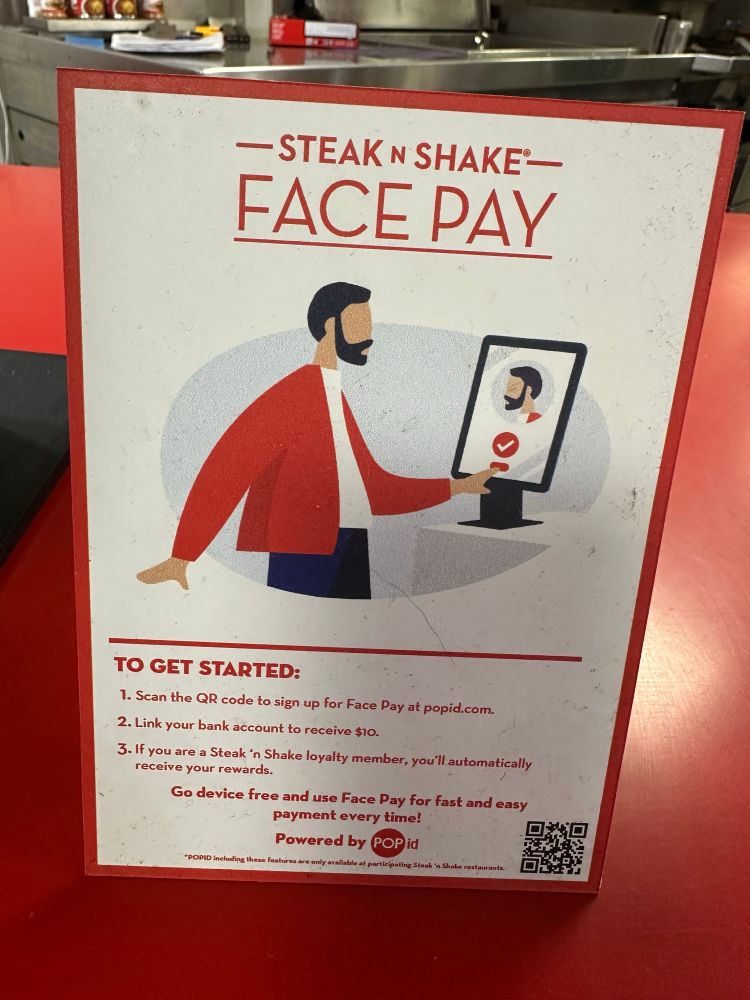 A counter sign at Steak n Shake guiding people through the process of linking their face to their bank account to pay for hamburgers. 
