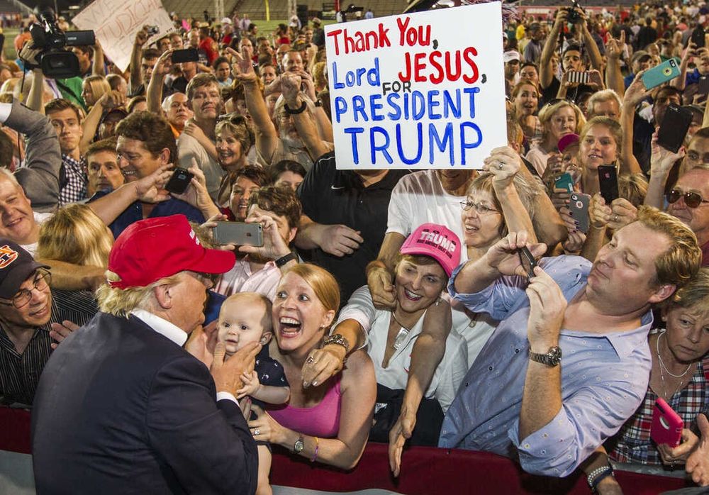 Des partisans de Trump déchainés et enthousiastes devant Trump : une pancarte tenue par une femme indique "Thank you, Lord Jesus for President Trump". 
