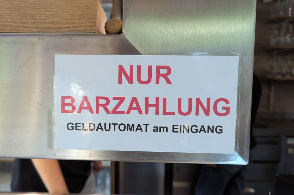 Laminierter Aushang an der Kasse: "NUR BARZAHLUNG. GELDAUTOMAT am EINGANG"