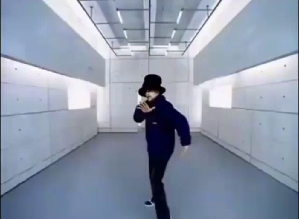 a man in a black top hat is dancing in a hallway .