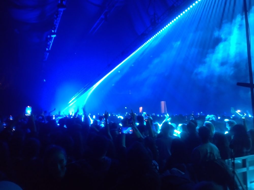 Crowded hall with stream of light down the centre, descending from the ceiling.