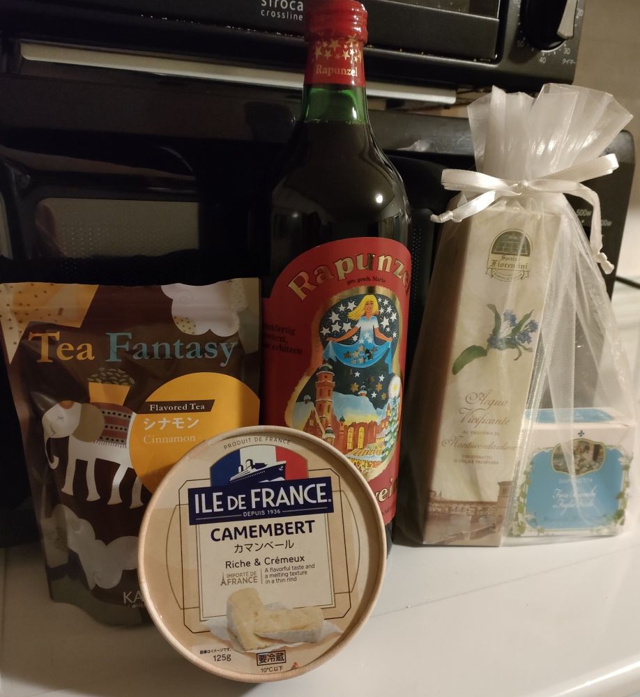 Photo of birthday gifts received: cinnamon flavored tea, camenbert cheese, a bottle of mulled wine and a bath set.