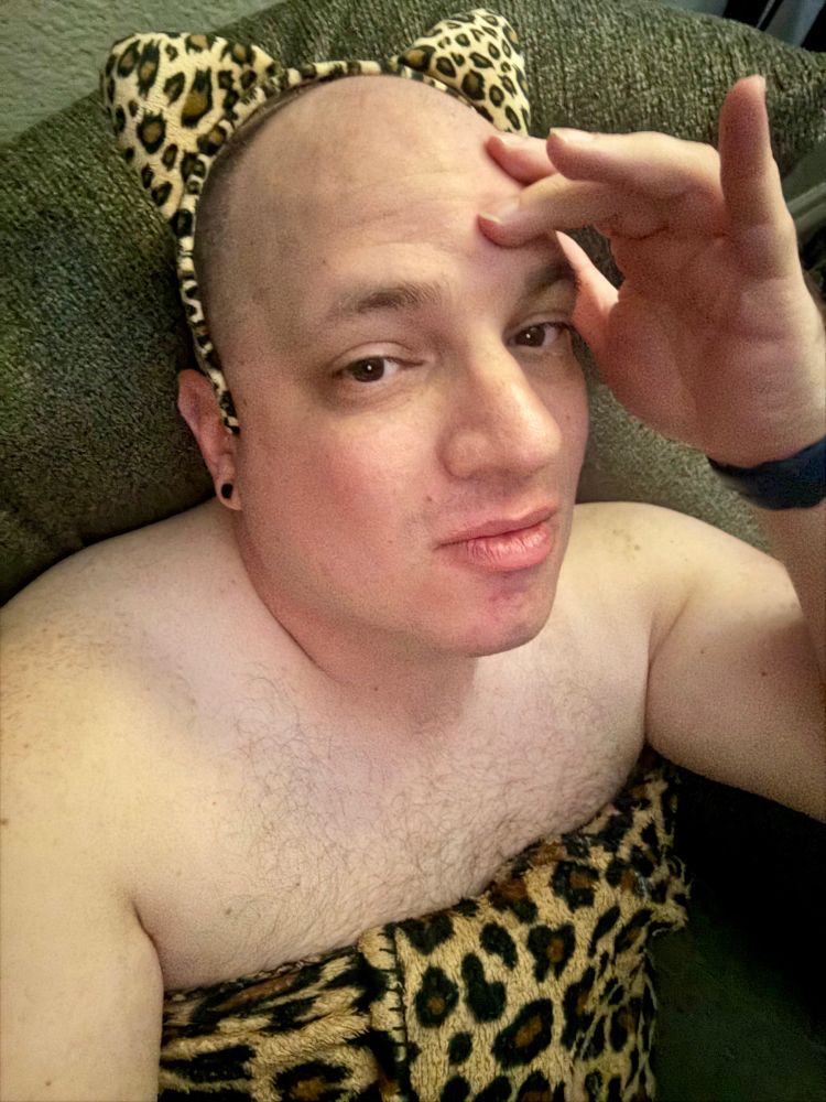Dude wrapped in cheetah print blanket with a cheetah print headband on his head. 
