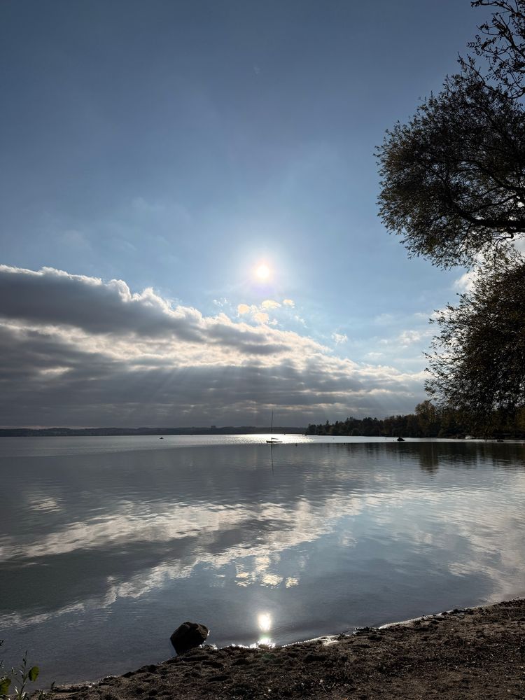 In einem ruhigen See spiegelt sich der Himmel, die Wolken, die Sonne. 