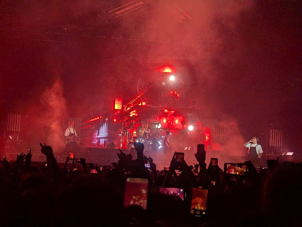 A concert scene with a projection of a steam train behind a metal band. 