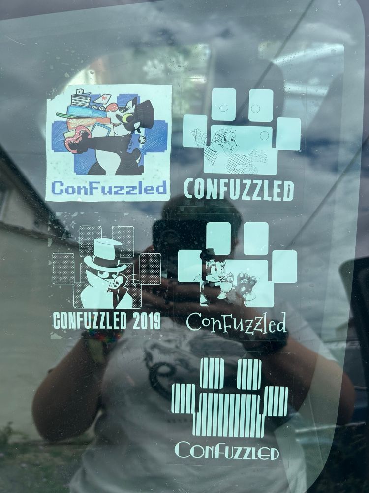 A section of white car decal stickers on a car windshield . They have the paw print logo of confuzeld a uk furry con 