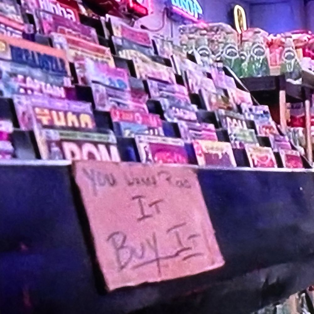 In a scene in ROBOCOP, a convenience store and approaches sales rack features comic books. Marvel’s ROM SPACEKNIGHT is visible in the front and appears largest in the frame. Sign on rack reads “You wanna read it BUY IT”.