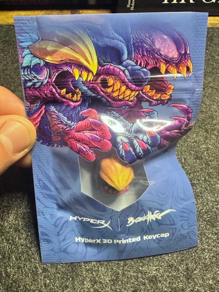 A monster themed key cap designed by Brock Hofer in its packaging. 
