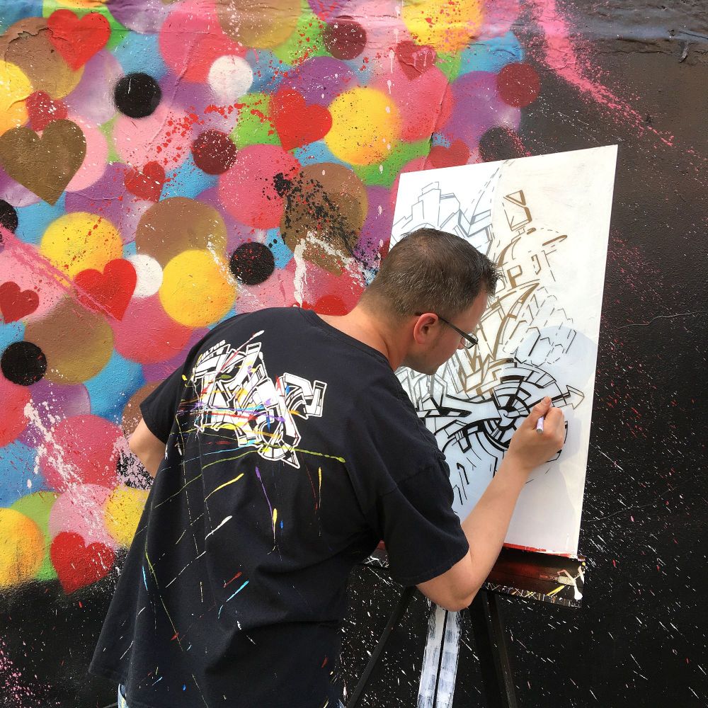 Artist David Lyman paints a canvas in front of a mural by Hektad for International Hip-Hop Day in the East Village in Manhattan, New York. 