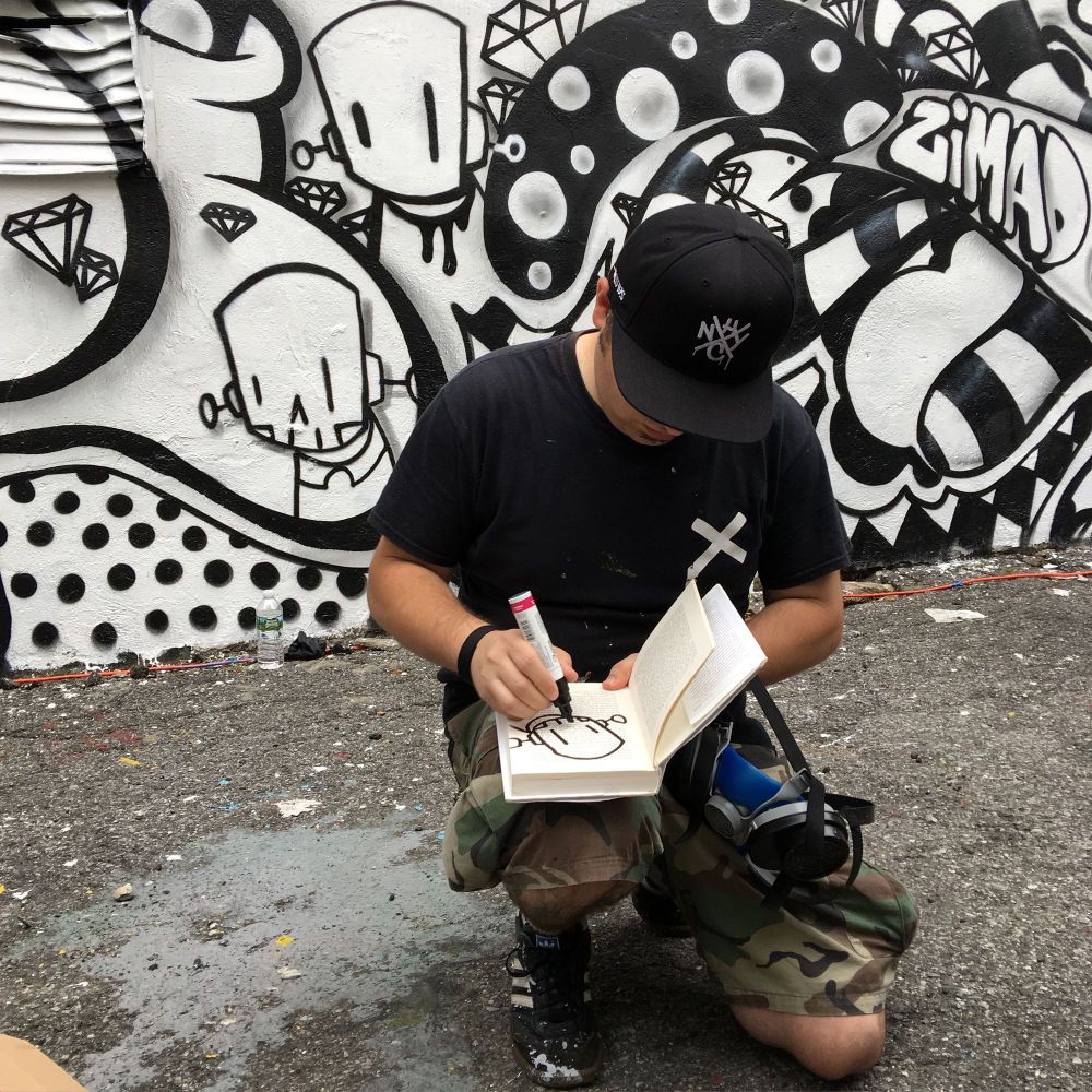 Artist ChrisRWK draws in a blackbook during a Secret Walls battle for the LISA Project in Little Italy in Manhattan, New York. 