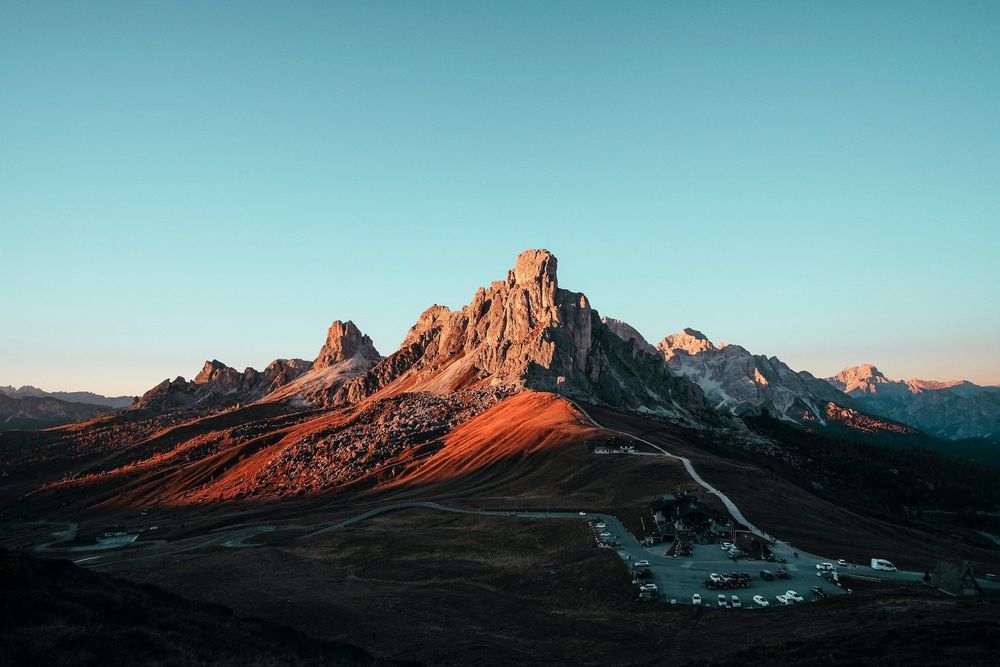 A breathtaking sunset over the Giau Pass mountains in Italy, casting warm hues across the serene landscape.