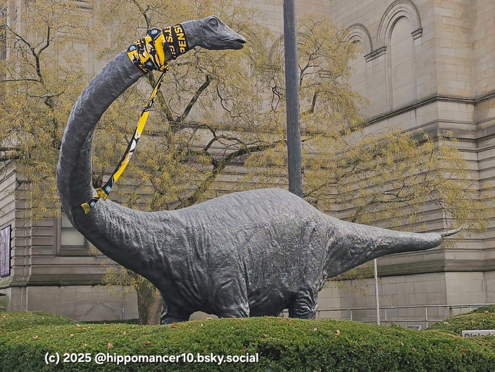 Giant dinosaur statue outside of the Carnegie Museums of Pittsburgh. It is wearing a black and gold scarf. Did it just wink at the photographer? 