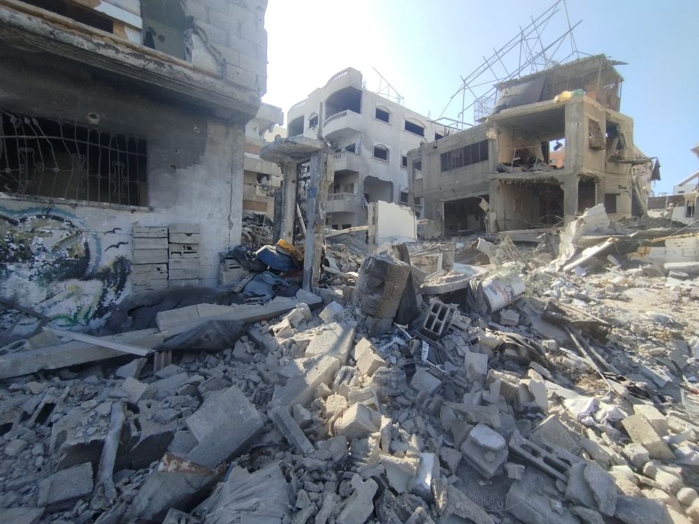 A completely destroyed my house in Gaza, reduced to rubble and dust, showing the aftermath of heavy bombing.