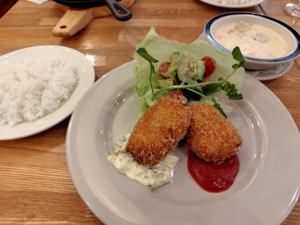 クリーム・コロッケが２つ載った皿の左にライス、右にシーフードのクリーム・スープ。