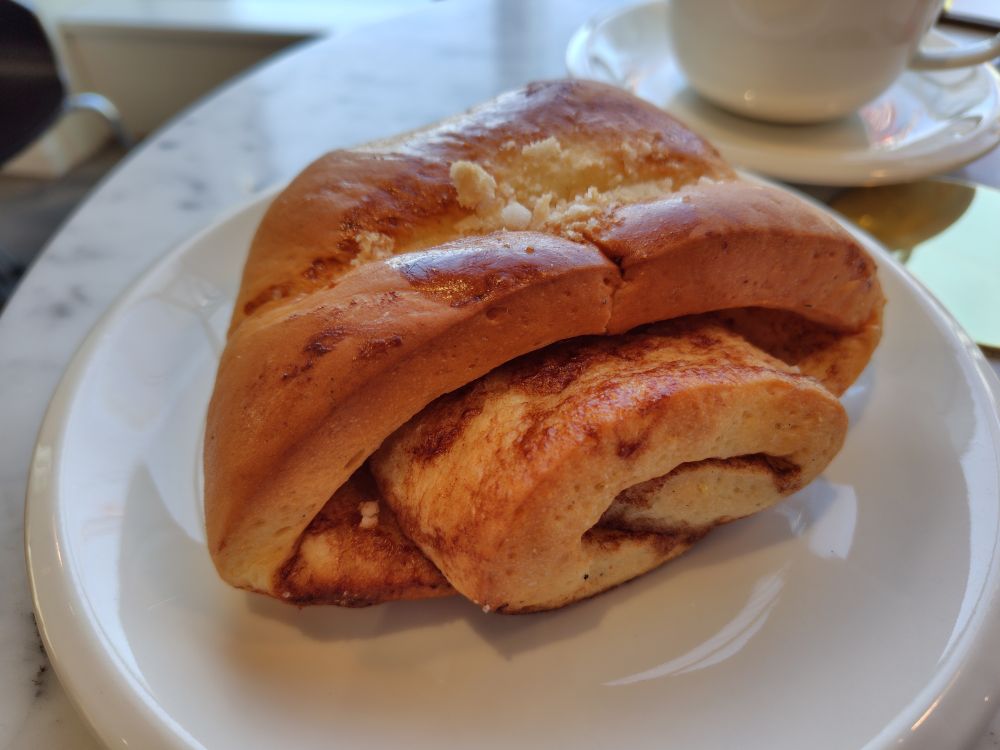 白い丸皿に載ったシナモンロールのアップ。シナモンが折り込まれた生地が縦に巻き込まれている。