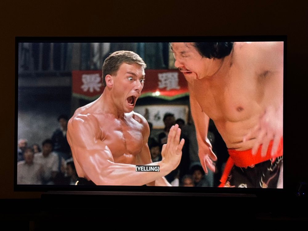 Jean-Claude Van Damme attacking an opponent in Bloodsport (with closed caption noting “yelling”) 