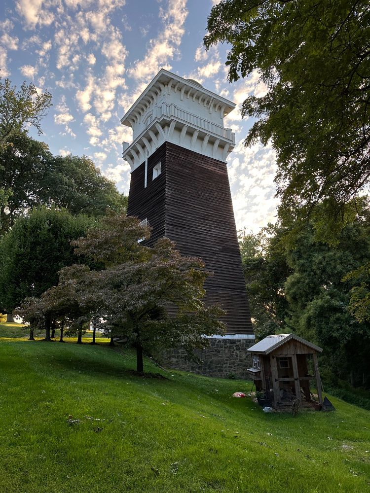 Photograph of an old tower structure with dark wood sides and a white top with balcony