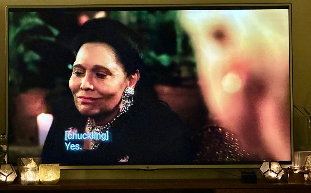 Image ID 1/2. Usha Khan, cast as Naheed Khan (mother of Diana’s then-lover British-Pakistani surgeon Dr. Hasnat Khan), looks at Lady Di, chuckling & then says “Yes.”