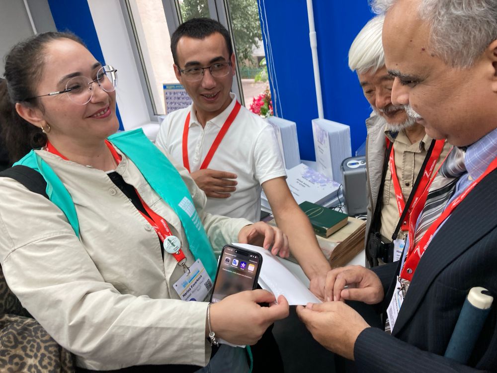 Marina - a Congress volunteer and translator - showing blind Congress attendee Dipendra Manocha a welcome to Kazakhstan which one of the team at the library had just created.