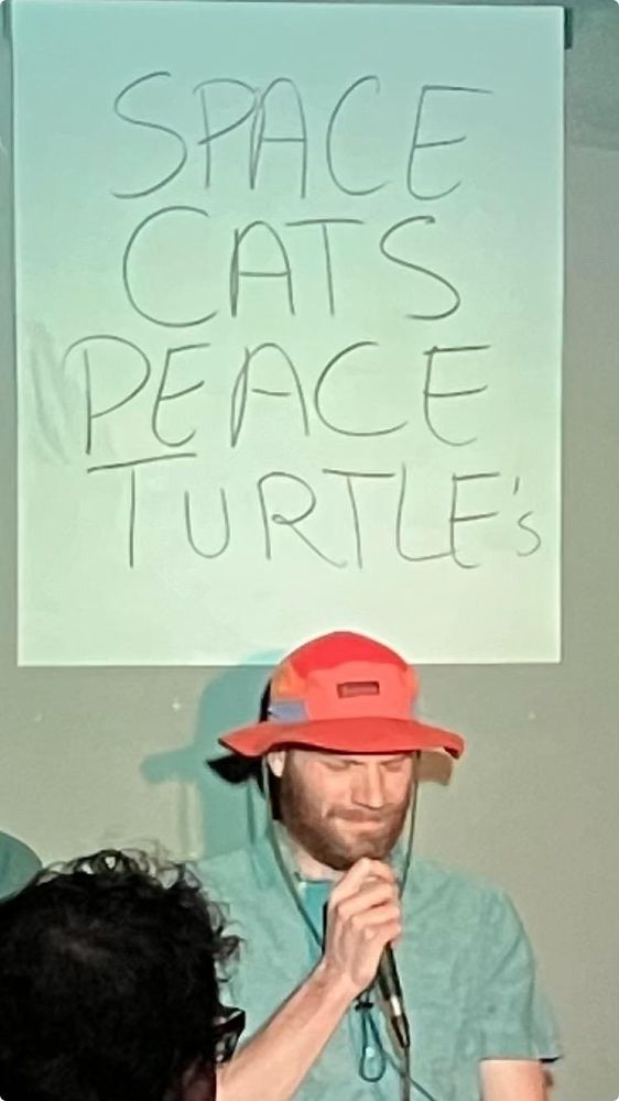 A strange man talking into a microphone in front of an audience