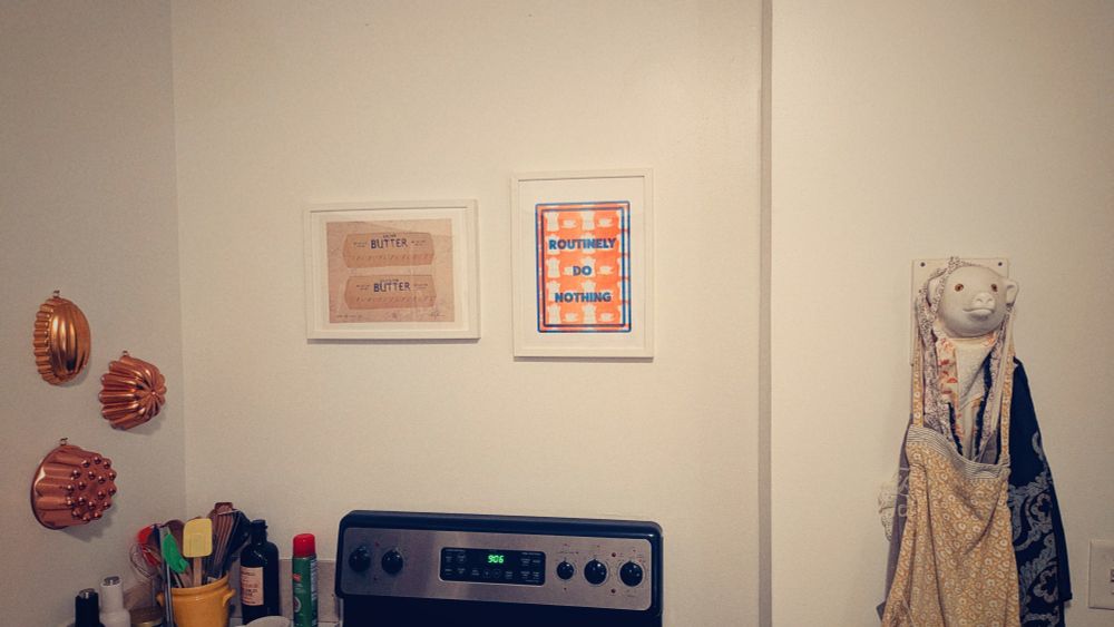 A mediocre white kitchen with a perfect pig face holding some aprons and a sign that says Routinely Do Nothing. There is also an illustration of butter.