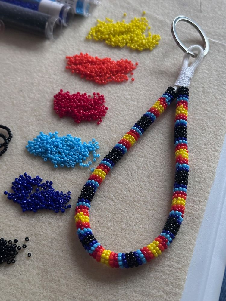 A bead wrapped wristlet keychain in black, red, orange, yellow, and blue