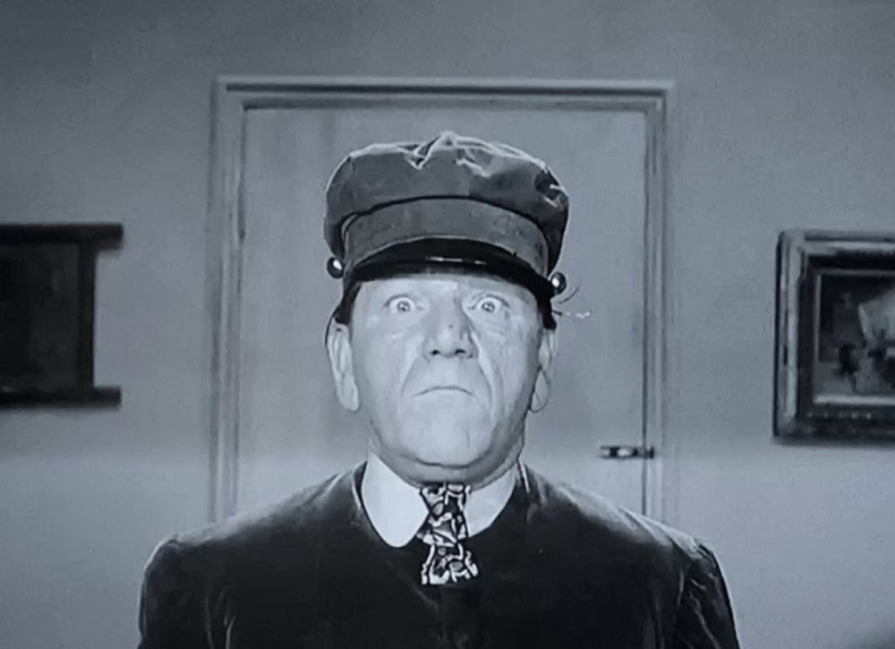 a black and white photo of a man wearing a hat and a tie