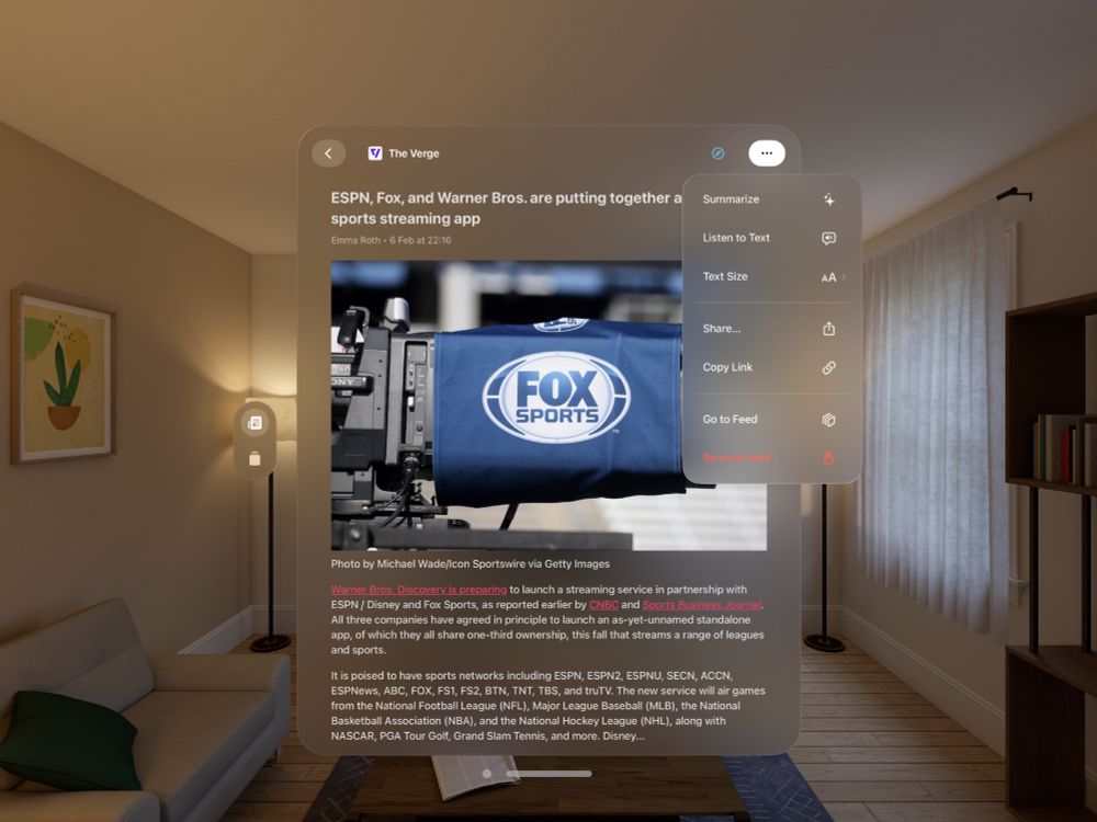 Screenshot of an article from The Verge being displayed in a portrait orientation window. A glass ornament on the left shows two buttons, for news and for feeds. A menu in the top right of the window is expanded, with the options to summarize the article, listen to the text, change text size, share, and more.