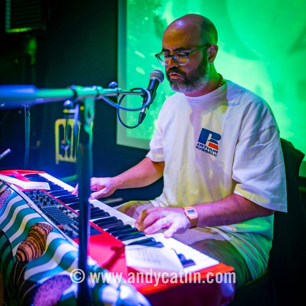 A musician playing a keyboard onstage during a concert