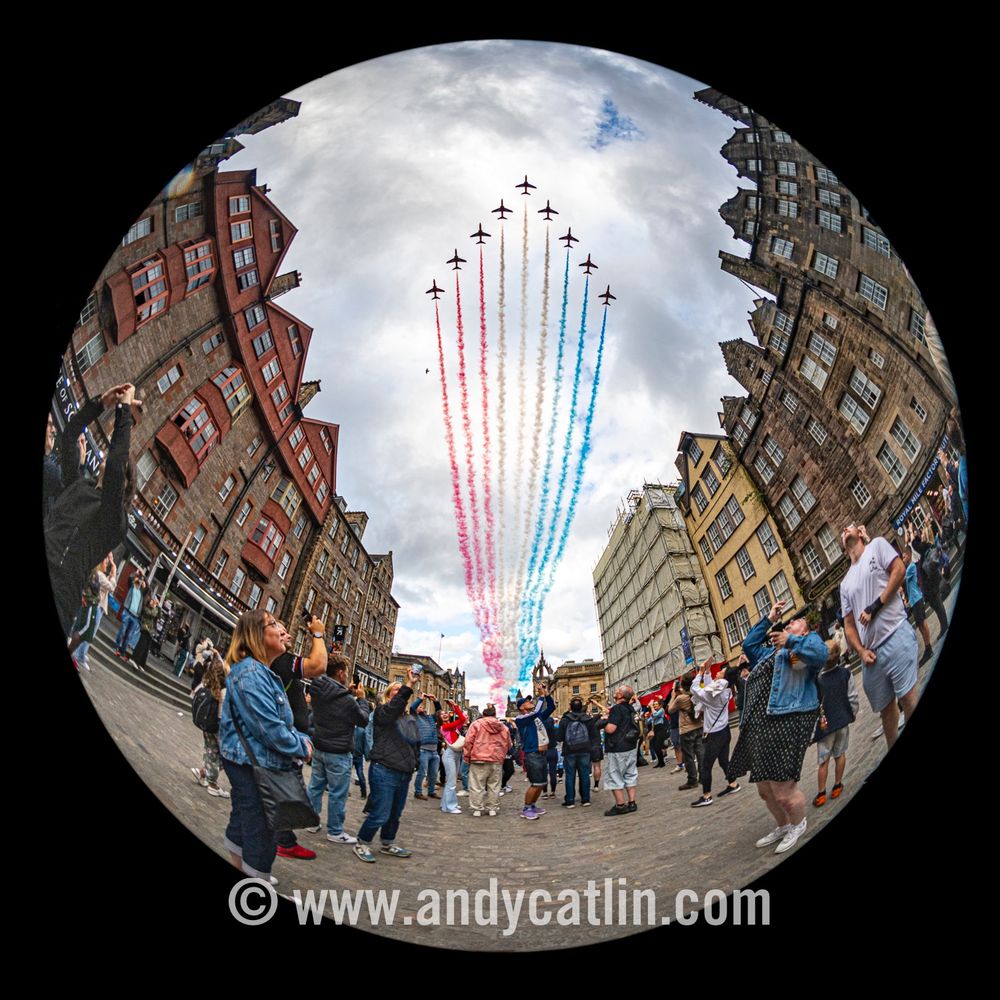 Nine military aircraft with multicoloured smoke trails fly in a arrow formation over Edinburgh city centre.