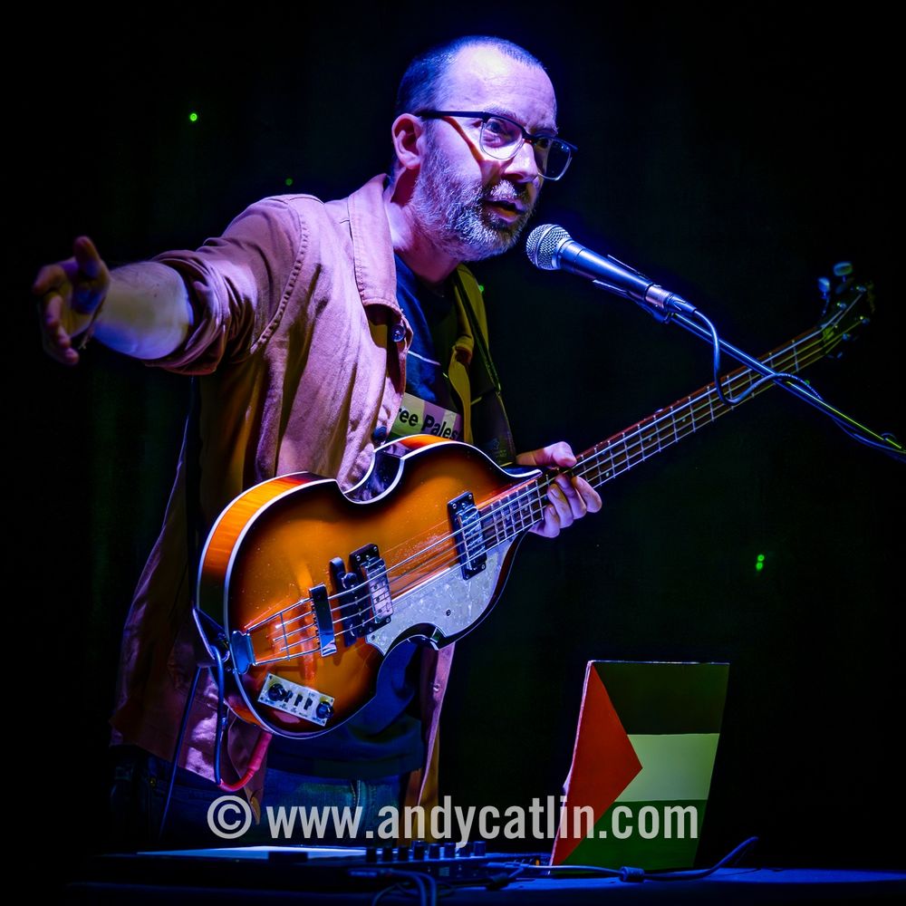 An electric bass guitarist playing onstage during a concert
