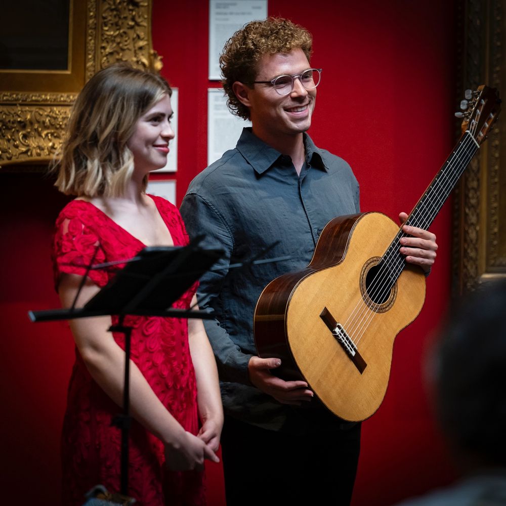 A classical music singer and guitarist performing in an art gallery