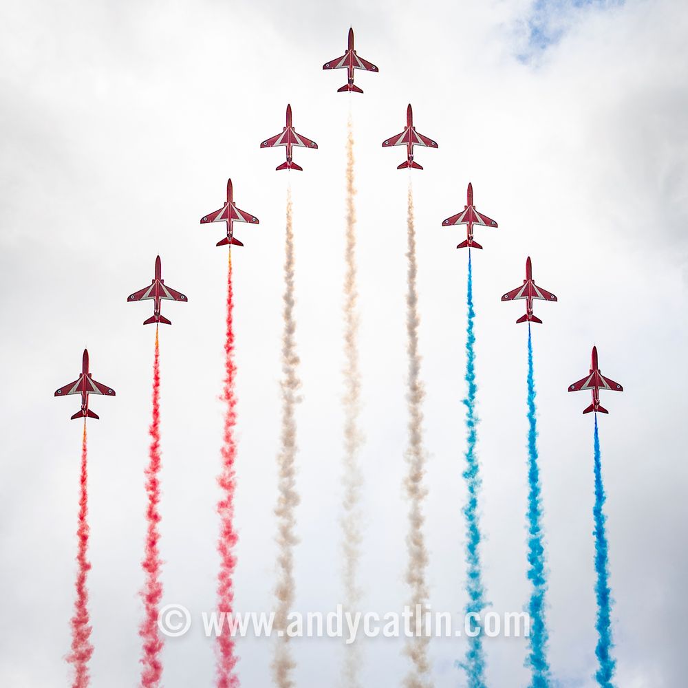 Nine military aircraft with multicoloured smoke trails fly in a arrow formation over Edinburgh city centre.