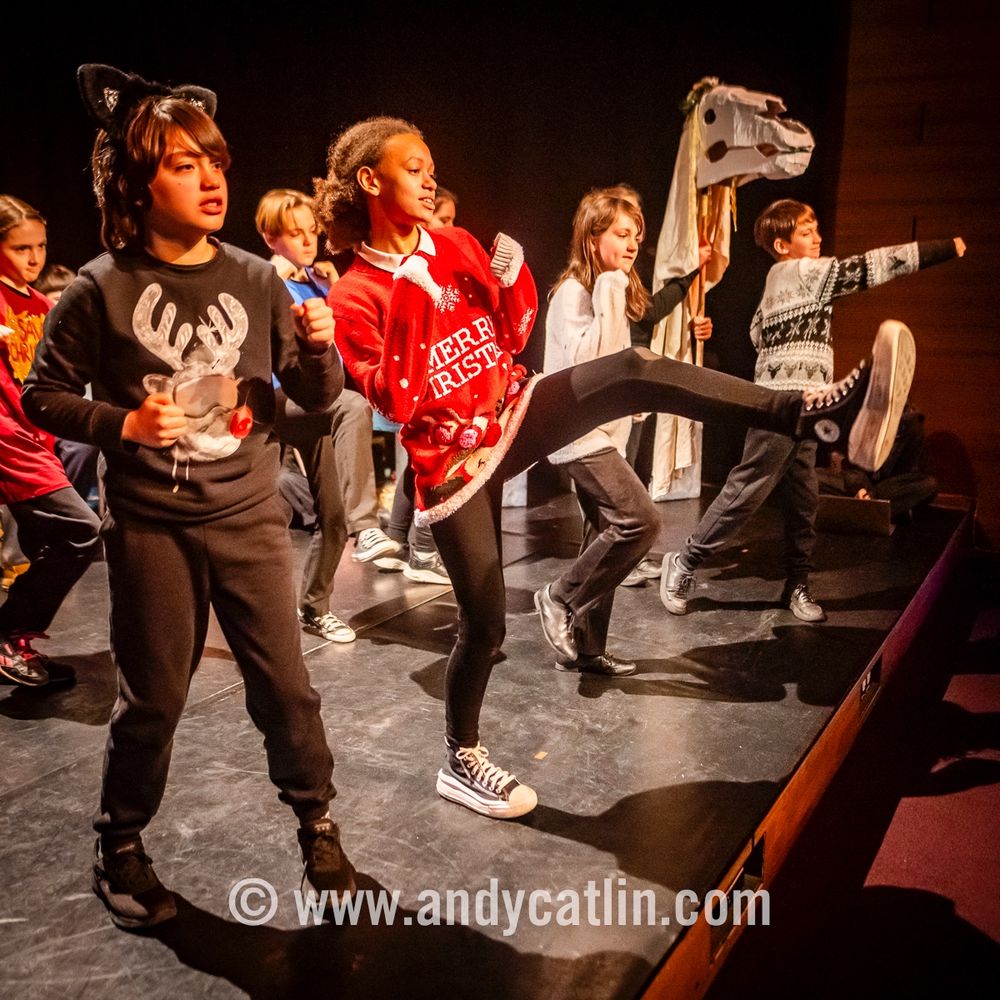 A group of young actors onstage kicking and punching out towards the audience