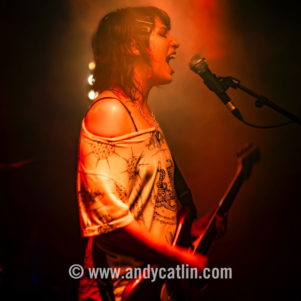 A singer playing an electric guitar onstage during a concert