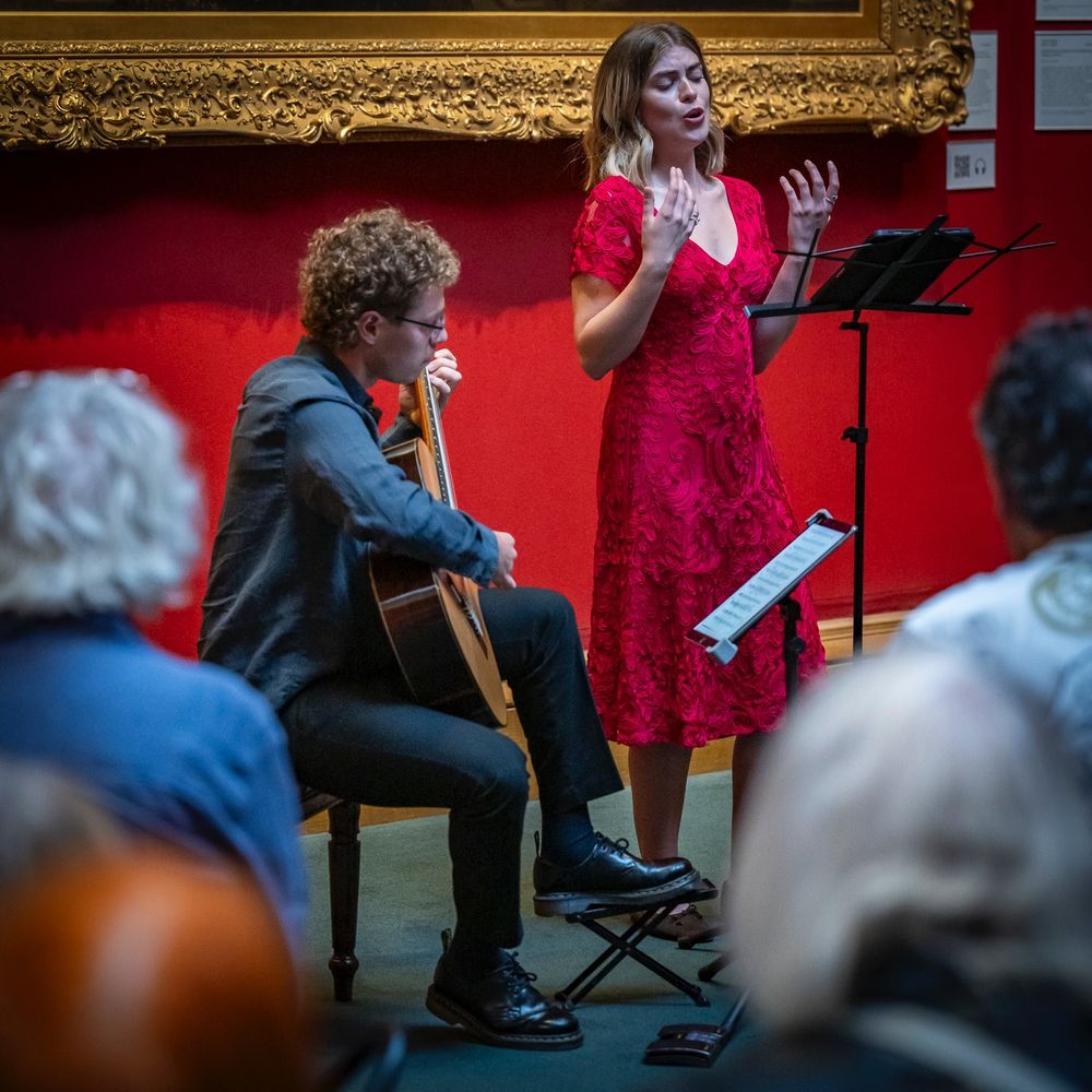 A classical music singer and guitarist performing in an art gallery