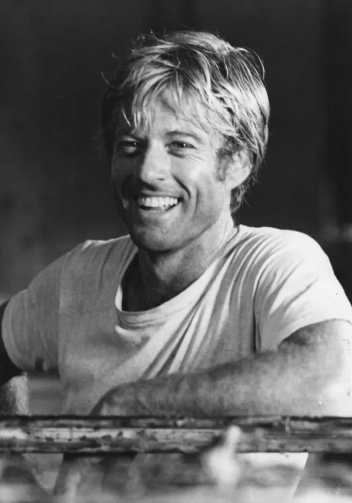 Black & White image of a young, handsome Robert Redford smiling.