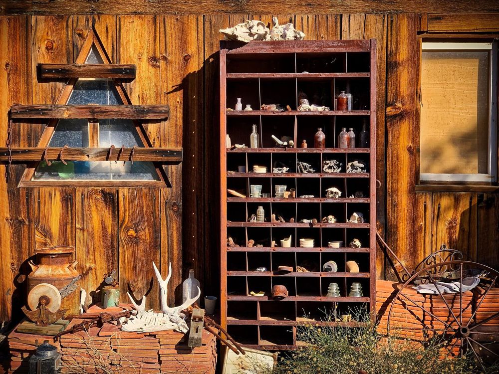 A rustic wooden wall with shelves displaying various bottles and artifacts at Techatticup Mine, Nelson, Nevada.