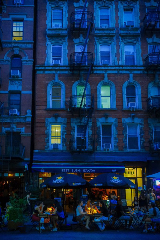 People dine beneath umbrellas outside a sushi restaurant on the Lower East Side, Manhattan, New York.